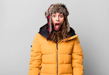 hispanic pretty woman looking very shocked or surprised. wearing an anorak. cold and winter concept