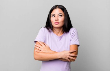 Güzel Latin bir kadın omuz silkiyor, kafası karışık ve kararsız, kolları bağlı ve şaşkın görünüyor.