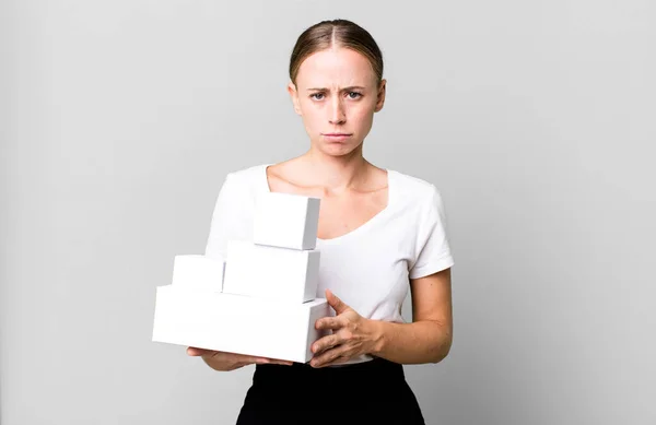 白人の可愛い女性は悲しい 動揺する 怒っている 白い箱のパッケージで側面を見ている — ストック写真