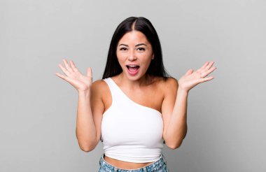 Güzel Latin kadın mutlu ve heyecanlı görünüyor. Beklenmedik bir sürprizle şoke olmuş. İki eli de açık.