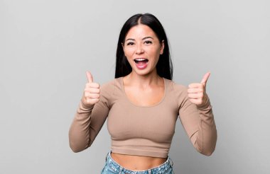 Güzel Latin kadın gülümsüyor mutlu, pozitif, kendinden emin ve başarılı, iki başparmağı da havada.