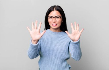 Güzel Latin kadın gülümsüyor ve arkadaş canlısı görünüyor, onuncu ya da onuncu numarayı gösteriyor, eli önde, geri sayıyor.