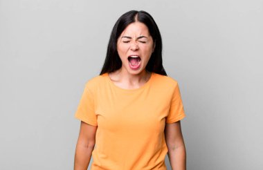 Güzel Latin kadın öfkeyle bağırıyor, agresif bir şekilde bağırıyor, stresli ve kızgın görünüyor.