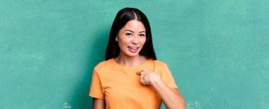 Güzel Latin kadın mutlu, gururlu ve şaşırmış görünüyor, neşeli bir şekilde kendini gösteriyor, kendinden emin ve kibirli hissediyor.