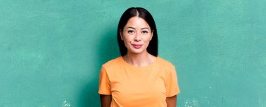 Güzel Latin kadın, pozitif ve kendinden emin gülümsüyor. Tatmin olmuş, arkadaş canlısı ve mutlu görünüyor.