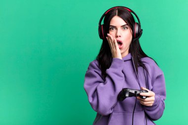 Kulaklık takan genç bir kadın joystick 'te video oyunu oynuyor.