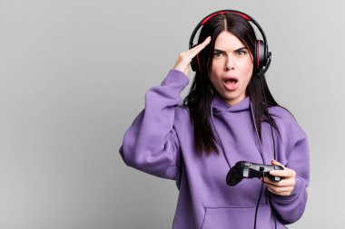 Kulaklık takan genç bir kadın joystick 'te video oyunu oynuyor.