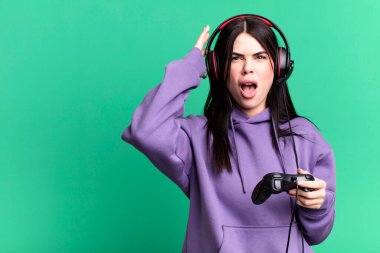 Kulaklık takan genç bir kadın joystick 'te video oyunu oynuyor.