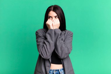 Genç ve güzel bir kadın endişeli, gergin, stresli ve korkmuş görünüyor. Tırnaklarını yiyor ve yanal fotokopi alanı arıyor.