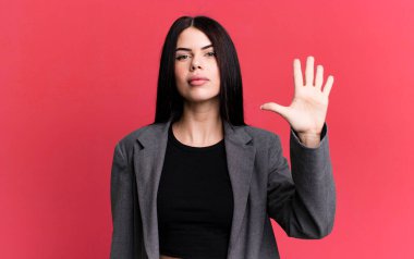 young adult pretty woman smiling and looking friendly, showing number five or fifth with hand forward, counting down