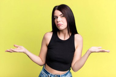 young adult pretty woman feeling clueless and confused, having no idea, absolutely puzzled with a dumb or foolish look