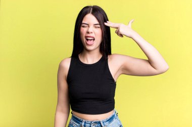 Genç ve güzel bir kadın mutsuz ve stresli görünüyor, intihar jesti elle silah işareti yapıyor, kafasını işaret ediyor.