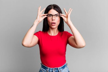 Genç, güzel bir kadın şok olmuş, şaşırmış ve şaşırmış hissediyor. Elinde şaşkın, inançsız bir bakışla gözlük tutuyor.