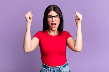 Genç ve güzel bir kadın mutlu, pozitif ve başarılı hissediyor, zaferi, başarıları veya iyi şansı kutluyor.