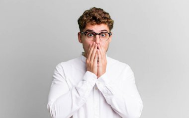 young adult caucasian man feeling worried, upset and scared, covering mouth with hands, looking anxious and having messed up