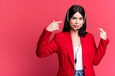 Kendi gülüşünü göstererek kendine güvenerek gülümsüyor. Kulaklık takan bir pazarlamacı.