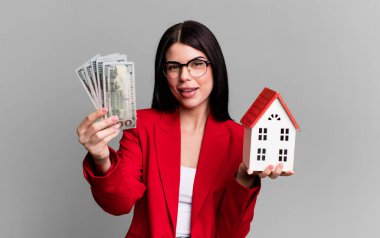 Dolar banknotları ve ev modeliyle genç ve güzel bir emlakçı.