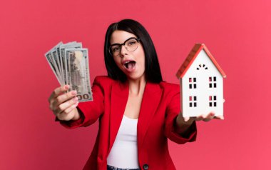 Dolar banknotları ve ev modeliyle genç ve güzel bir emlakçı.