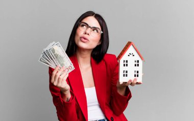 Dolar banknotları ve ev modeliyle genç ve güzel bir emlakçı.