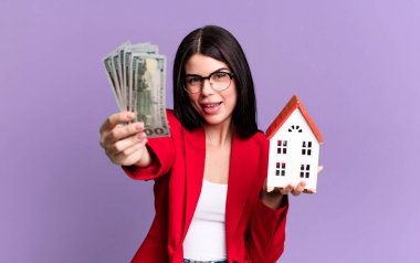 Dolar banknotları ve ev modeliyle genç ve güzel bir emlakçı.