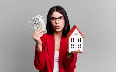 Dolar banknotları ve ev modeliyle genç ve güzel bir emlakçı.