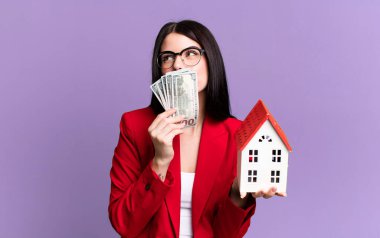 Dolar banknotları ve ev modeliyle genç ve güzel bir emlakçı.