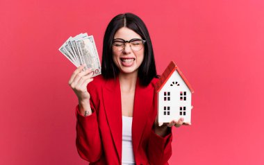 Dolar banknotları ve ev modeliyle genç ve güzel bir emlakçı.