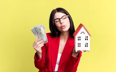 Dolar banknotları ve ev modeliyle genç ve güzel bir emlakçı.