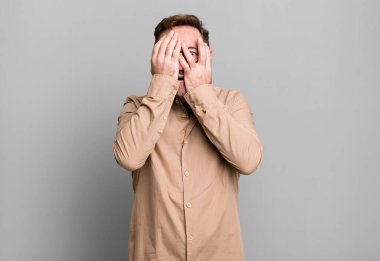 Yüzü ellerle kaplamak, parmaklarının arasından bakmak şaşırmış bir ifadeyle yan tarafa bakmak.