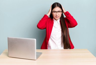 Güzel Asyalı kadın stresli, endişeli ya da korkmuş, elleri başının üstünde. iş masası konsepti