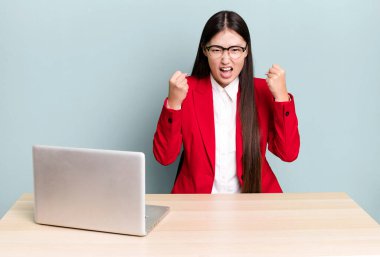 Güzel Asyalı kadın sinirli bir ifadeyle agresif bir şekilde bağırıyor. iş masası konsepti