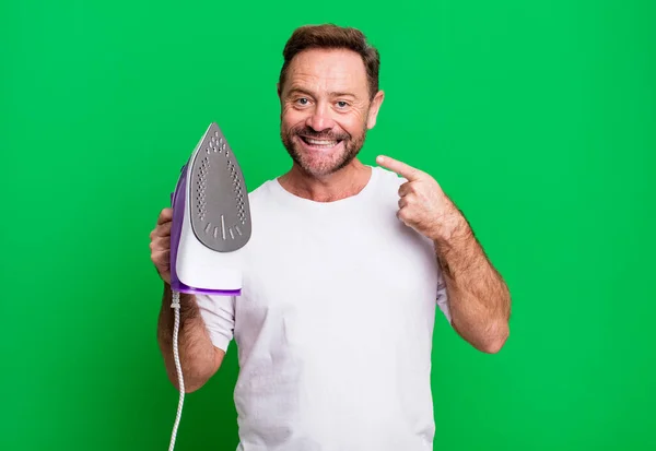 middle age man smiling confidently pointing to own broad smile. housekeeper concept