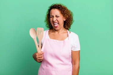 Oldukça orta yaşlı, neşeli ve asi tavırlı, şaka yapan ve dilini dışarı çıkaran bir kadın. ev hanımı şef konsepti