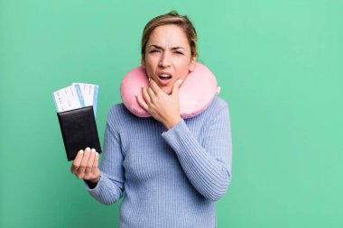 Güzel sarışın kadın, ağzı ve gözleri sonuna kadar açık ve eli çenesinde. uçuş yolcu kavramı