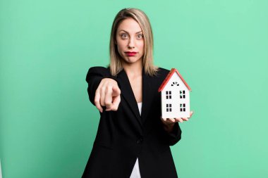 pretty blonde woman pointing at camera choosing you. real state concept