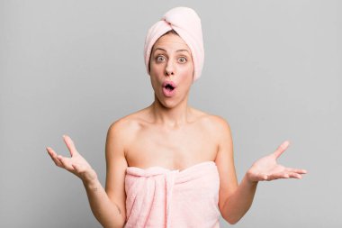pretty blonde woman amazed, shocked and astonished with an unbelievable surprise. bathrobe and beauty concept
