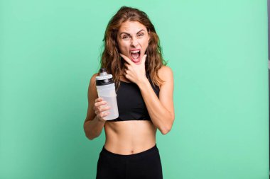 Ağzı ve gözleri açık ve eli çenesinde olan Latin kökenli güzel bir kadın. fitness ve egzersiz konsepti