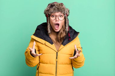 hispanic pretty woman feeling extremely shocked and surprised wearing anorak. cold and winter concept
