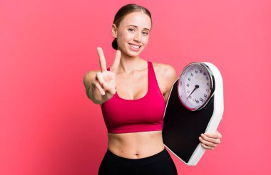 caucasian pretty woman smiling and looking happy, gesturing victory or peace. fitness and diet concept
