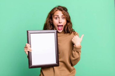 hispanic pretty young woman with a blank frame copy space