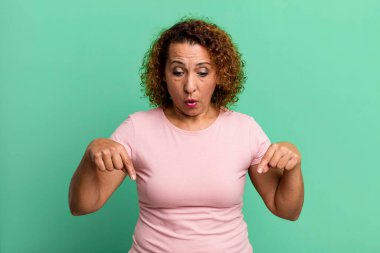 Orta yaşlı İspanyol bir kadın şok olmuş, ağzı açık ve şaşırmış hissediyor. İnançsızlık ve şaşkınlık içinde bakıyor ve işaret ediyor.