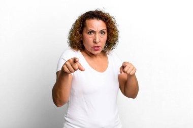 Orta yaşlı, Latin bir kadın kameraya iki parmağıyla ve kızgın bir ifadeyle sana görevini yapmanı söylüyor.