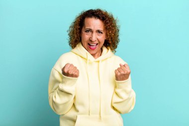 Orta yaşlı İspanyol kadın zaferle bağırıyor, gülüyor, mutlu ve heyecanlı hissediyor başarıyı kutlarken.