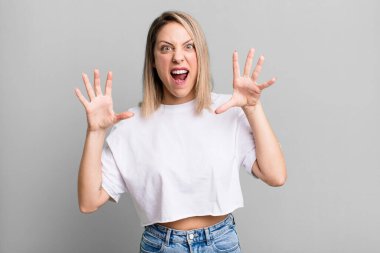blonde adult woman screaming in panic or anger, shocked, terrified or furious, with hands next to head