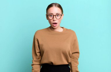 Şok olmuş ya da şaşırmış görünüyor, ağzı açık bakıyor ve 