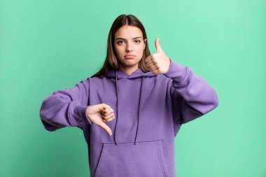 pretty young adult woman feeling confused, clueless and unsure, weighting the good and bad in different options or choices