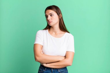 pretty young adult woman feeling sad, upset or angry and looking to the side with a negative attitude, frowning in disagreement