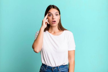 pretty young adult woman looking surprised, open-mouthed, shocked, realizing a new thought, idea or concept