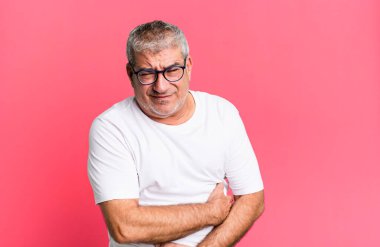 Orta yaşlı bir adam endişeli, hasta, hasta ve mutsuz hissediyor. Ağrılı bir mide ağrısı ya da grip geçiriyor.