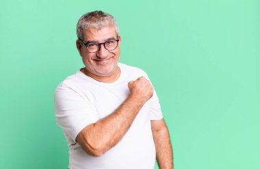 Orta yaşlı bir adam mutlu, pozitif ve başarılı hissediyor, bir meydan okumayla karşılaştığında ya da iyi sonuçları kutladığında motive oluyor.